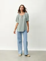 Blusa blanca de mangas cortas con escote redondo y lazos.