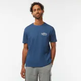 Camiseta azul de manga corta con estampado pequeño en el pecho que dice 'In Sun We Trust Altagracia'.