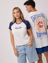 Remera azul marino de algodón con mangas cortas raglán blancas con ribete naranja y estampado ovalado con el logo de Rusty en el pecho.