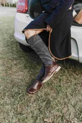 Botas altas de cuero marrón combinadas con gamuza blanca con estampado de vaca, forradas en cuero y con cierre de bronce.