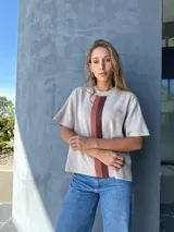 Buzo color beige con rayas verticales marrones, tejido en hilo, de mangas cortas y cuello redondo.