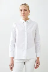 Camisa blanca de corte clásico, con cuello camisero, mangas largas con puños abotonados y cierre frontal con botones.
