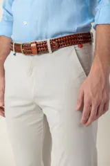 Pantalón de vestir color gris claro, de corte slim fit, con bolsillos laterales y traseros. Se ajusta a la cintura con cinturón de cuero marrón.