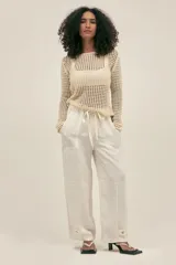 Pantalón de trabajo color crema, de corte relajado, confeccionado en lino y tencel. Con bolsillos laterales, cintura elástica, cordón ajustable y detalle regulable en el tobillo.