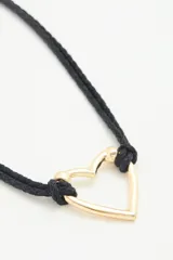 Collar con cordón negro trenzado y dije de corazón dorado.