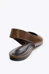 Zapato destalonado tipo bailarina, color marrón, de piel, con punta fina y tira trasera con elástico lateral.