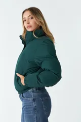 Campera puffer verde oscuro de nylon, con cuello alto, cierre frontal con cremallera, bolsillos laterales y cintura ajustable con cordón.