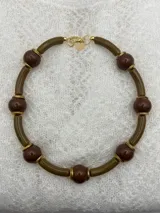 Collar corto con cuentas redondas color lila y cuentas cilíndricas color verde oliva, separadas por anillos dorados.