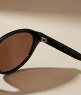 Gafas de sol con montura ovalada de color negro y lentes polarizadas color marrón degradado. Fabricadas con material bio-based G850 y patillas de Propionato de Celulosa.