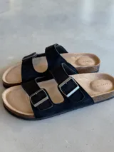 Sandalias negras con dos tiras anchas ajustables con hebillas metálicas plateadas.