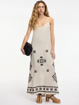 Vestido largo color beige con breteles finos y bordado de motivos geométricos en negro.