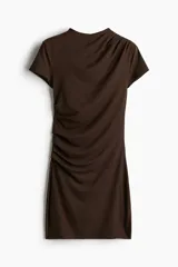 Vestido corto marrón de punto elástico, con cuello elevado corto, mangas cortas y corte ajustado. Presenta pliegues en un hombro y en un lateral para crear un efecto drapeado.