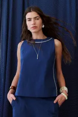 Top sin mangas color rosa pálido, con cuello redondo y vivos en color marrón oscuro en el cuello y a lo largo de las costuras laterales.