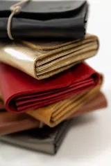 Billetera tipo sobre de cuero negro con cierre de elástico, separaciones internas y bolsillo con cierre para monedas.