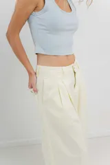 Pantalón 3/4 estilo palazzo confeccionado en denim liviano de tono amarillo pastel, tiro medio con pliegues delanteros, bolsillos delanteros y traseros aplicados, con detalle de logo metálico PEACH en la parte posterior.