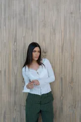 Remera de encaje blanca con mangas largas y broche metálico en el centro. Incluye musculosa de lycra blanca como forro.