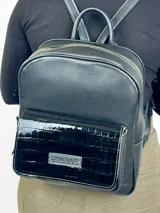 Mochila grande de cuero negro con bolsillo frontal de charol y cierre superior.