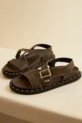 Sandalias de cuero color marrón con tachas en la suela y ajuste de hebilla en el empeine.