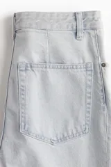 Pantalón jean celeste de denim de algodón rígido, corte ajustado de cintura a muslo y acampanado de rodilla a bajo, con cinco bolsillos, cierre y botón.