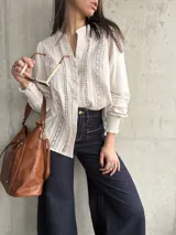 Camisa color beige de lino con detalles de broderie en el frente y mangas largas con puños elásticos.