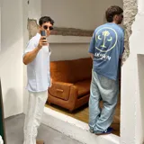 Camiseta azul de algodón de corte oversize, con estampado en la espalda de un círculo amarillo con una palmera y texto en blanco.