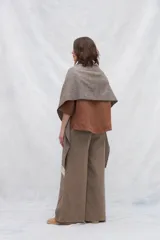 Chal de lana fina sin teñir, con calce en hombros, abrochadura con alamar de fieltro, bolsillos de cuero y terminación con flecos. Diseño exclusivo de Don Baez, hecho en Uruguay.