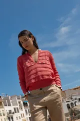 Sweater de punto negro con detalle de calados y lazo en el escote. Tiene ribetes con volados en contraste en el cuello y puños.