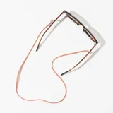 Correa para lentes de cuero sintético color naranja, con terminales doradas y enganches transparentes. Incluye dije redondo dorado con el logo de la marca.