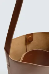 Bolso tipo shopper negro fabricado en piel, con asa de hombro y cierre magnético.