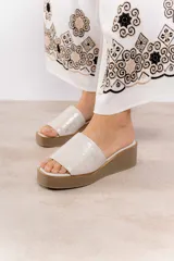 Sandalia con plataforma y taco de 5 cm, confeccionada en cuero color crudo.