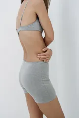 Bralette gris confeccionado en mezcla de viscosa, con escote redondo, tirantes finos ajustables y detalle de costuras marcadas con acabados en ondas. Cierre en espalda con ganchos metálicos.