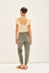 Pantalón tipo babucha color verde militar, con ajuste en tobillos y cintura regulable con cordón a tono. Confeccionado en gabardina elastizada, la cintura y los puños están realizados en flame. Cuenta con bolsillos diagonales en el frente y bolsillos con solapa y botón en la parte trasera.