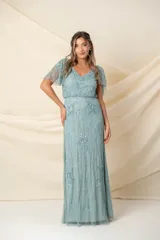 Vestido largo de tul bordado color verde agua, corte a la cintura y falda amplia. Las mangas son desmontables mediante broches, permitiendo usarlo sin mangas y combinarlo con un chal o túnica.