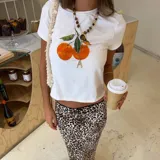 Remera blanca de algodón con estampado de dos naranjas con hojas verdes.