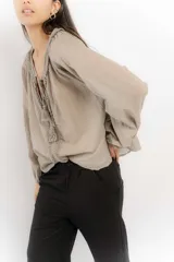 Blusa rosa de algodón con escote en V con cordones y detalle de volados.