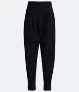 Pantalón zanahoria de crepé negro con pliegues, corte de sastrería, trabillas en la cintura y abertura con botón y cremallera.