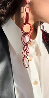 Aros colgantes hechos a mano con canutillos rojos y aritos de acero plateado.