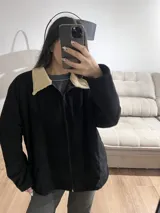Campera negra de pana con cuello beige, cierre frontal y bolsillos laterales.