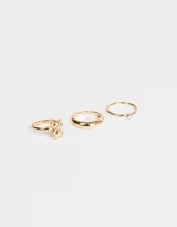 Set de tres anillos dorados de metal. Uno con forma de oso, otro liso y otro con strass.