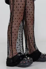 Pantalón negro acampanado de encaje con pequeños motivos florales.