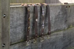 Cinturón marrón de cuero vacuno con hebilla metálica dorada y detalle de costuras blancas.
