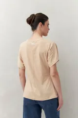 Remera blanca de manga corta con bordado frontal "C’est la vie", calce relajado y frunces laterales.