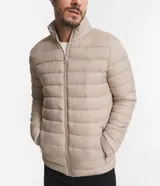 Campera puffer ultraligera color beige, con cuello alto, cierre por cremallera y bolsillos con cremallera. Incluye bolso de almacenamiento.