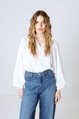 Camisa blanca de mangas largas abullonadas, con cuello mao y cierre frontal con botones.