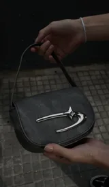 Mini bag gris con correa fina y cierre con forma de gancho plateado.