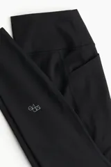 Calzas deportivas negras de tiro alto, confeccionadas en tejido funcional ShapeMove™ con bolsillos laterales.