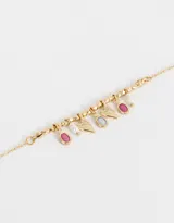 Pulsera dorada con cadena de eslabones, cuentas y dijes colgantes con forma de corazón, óvalo y perla.