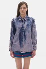 Camisa de jean azul con lavado gastado, corte oversized, manga larga y cierre frontal con botones.