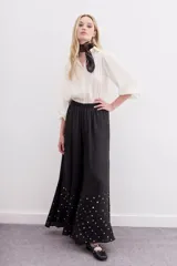 Pantalón amplio de viscosa color negro, con caída fluida, cintura elastizada y lentejuelas en la botamanga.