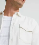 Camisa blanca de manga larga, confeccionada en terciopelo con cuello clásico y bolsillos frontales.